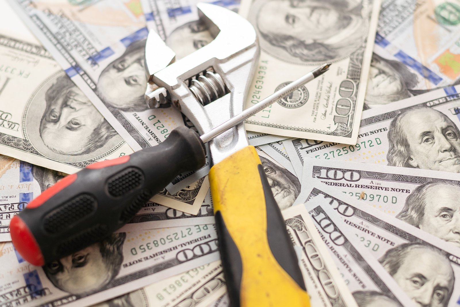 Concept of fixing currency of money and tools. Wrench, Pliers, screwdriver and dollars on a gray background